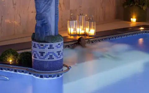 Bañista relajándose en la piscina del spa con faroles y velas del Hotel Carlos I Silgar
