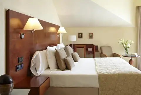 Habitación con cama de matrimonio y zona de estar abuhardillada del Hotel Carlos I Silgar