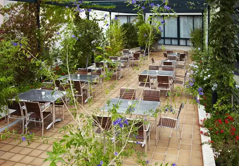 Terraza ajardinada con mesas y plantas trepadoras en el Hotel Carlos I Silgar
