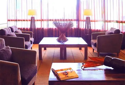 Salón con butacas tapizadas, mesas bajas y lámparas de pie en el Eurostars Isla de la Toja
