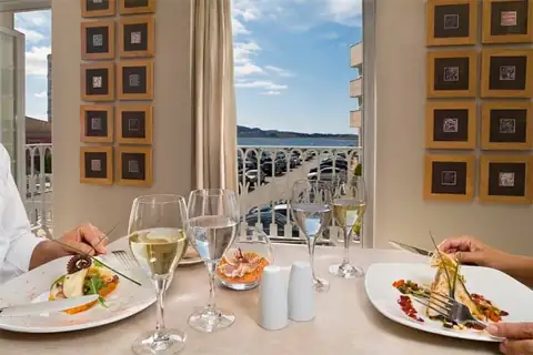Mesa servida con platos de pescado y copas de vino junto a la ventana del Eurostars Isla de la Toja