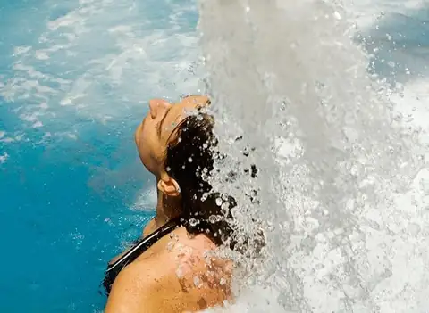 Bañista recibiendo el chorro de un cañón de agua sobre la espalda en el Eurostars Louxo Talaso
