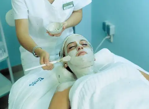 Terapeuta aplicando una mascarilla facial a una clienta en el spa del Eurostars Louxo Talaso