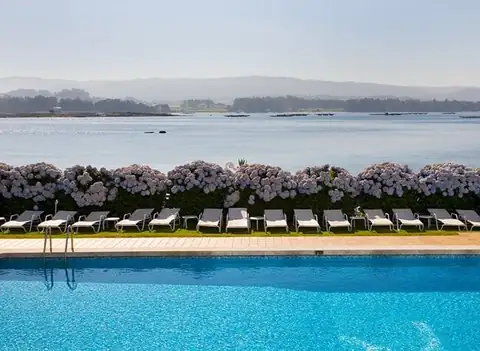 Piscina exterior con tumbonas, hortensias y vistas a la ría en el Eurostars Louxo Talaso