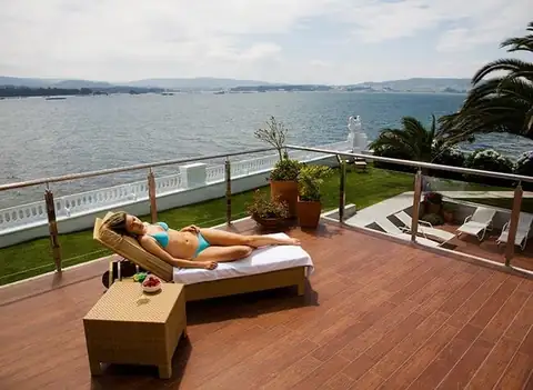 Huésped tomando el sol en una terraza de madera con vistas al mar del Eurostars Louxo Talaso
