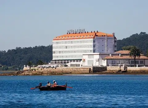 Edificio del Eurostars Louxo Talaso visto desde la ría, con una barca de remos en primer plano