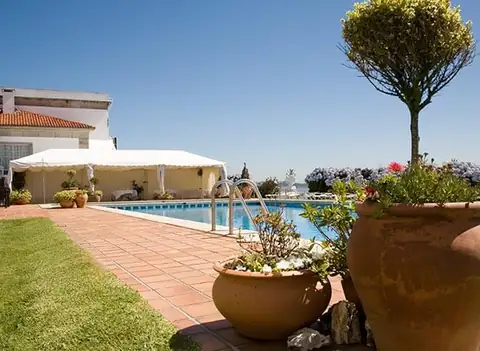Piscina exterior con macetas de barro y césped junto al edificio del Eurostars Louxo Talaso