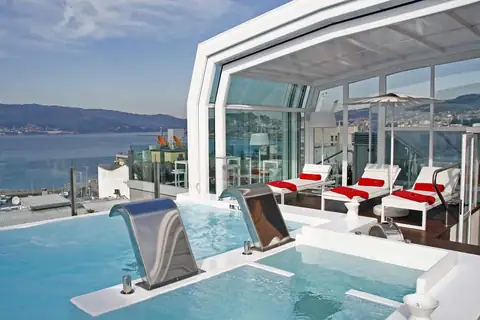 Piscina con cascadas y tumbonas rojas en la terraza panorámica del Gran Hotel Nagari de Vigo