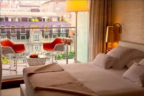 Habitación con terraza y sillas rojas con vistas a edificios de Vigo en el Gran Hotel Nagari