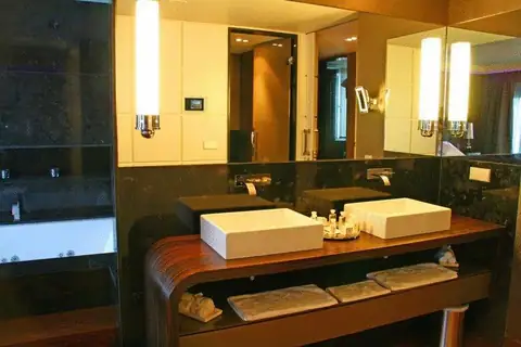 Baño con doble lavabo de encimera y mueble de madera oscura en el Gran Hotel Nagari