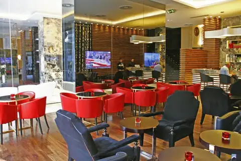 Cafetería del hotel con sillones rojos y negros, mesas bajas y barra en el Gran Hotel Nagari