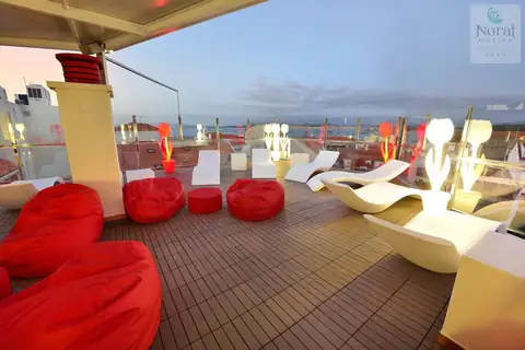Terraza chill out con puffs rojos y tumbonas blancas en la azotea del Hotel Norat Marina & Spa
