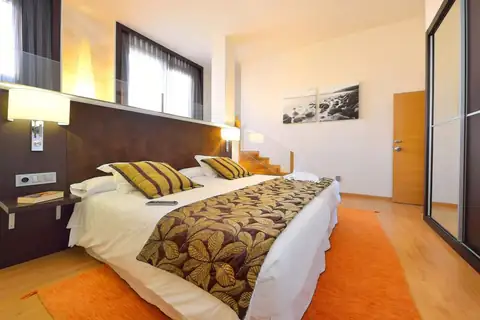 Habitación doble luminosa con cabecero de madera y suelo claro en el Hotel Norat Marina & Spa
