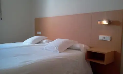 Habitación con dos camas y cabecero de madera en los Apartamentos Manzaneda