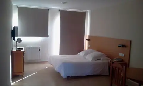 Dormitorio luminoso con cama doble y estores en los Apartamentos Manzaneda