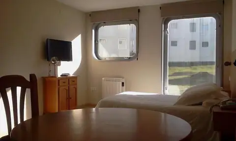 Apartamento con mesa de comedor, cama y grandes ventanas en la Estación de Montaña Manzaneda