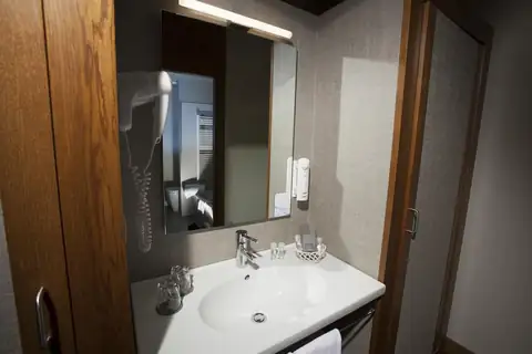 Baño de habitación con lavabo, espejo y secador en el Hotel Spa Attica21 Vilalba