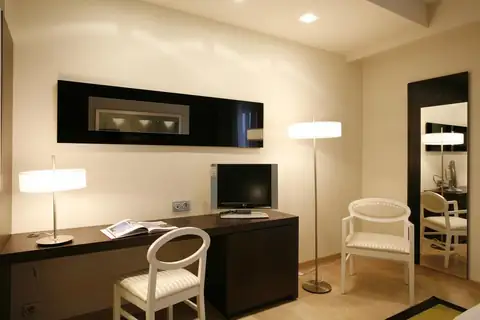 Zona de escritorio con televisión, lámpara de pie y sillas en una habitación del Hotel Bienestar Moaña