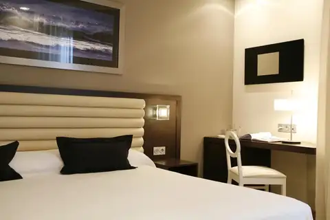 Habitación doble con cojines negros, escritorio y cuadro marino en el Hotel Bienestar Moaña
