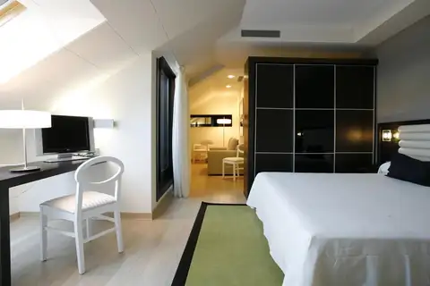 Habitación abuhardillada con cama doble, escritorio y armario en el Hotel Bienestar Moaña