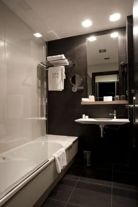 Baño con bañera, lavabo suspendido y paredes oscuras en una habitación del Hotel Bienestar Moaña