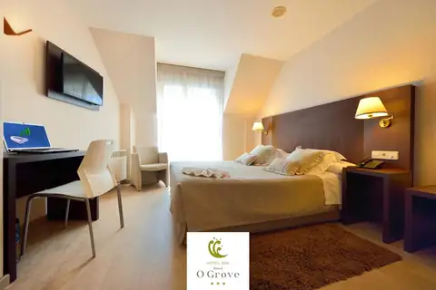 Habitación doble con cama de matrimonio, escritorio y televisor en el Hotel Spa Norat O Grove