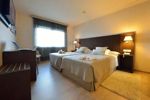 Habitación con dos camas, cabecero de madera oscura y ventanal en el Hotel Spa Norat O Grove