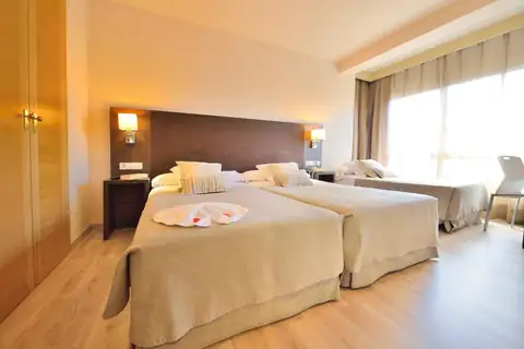 Habitación luminosa con dos camas y toallas en forma de cisne en el Hotel Spa Norat O Grove