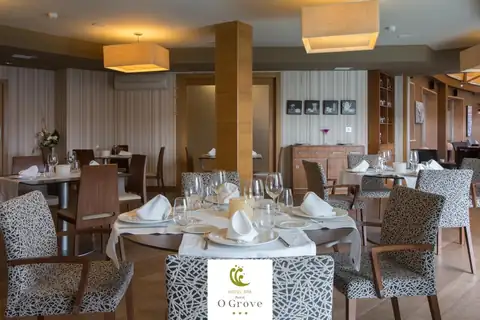Comedor con mesas vestidas, sillas tapizadas y lámparas en el Hotel Spa Norat O Grove