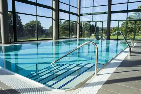 Piscina interior con escaleras y ventanales al bosque del Exe Vía Argentum en Silleda