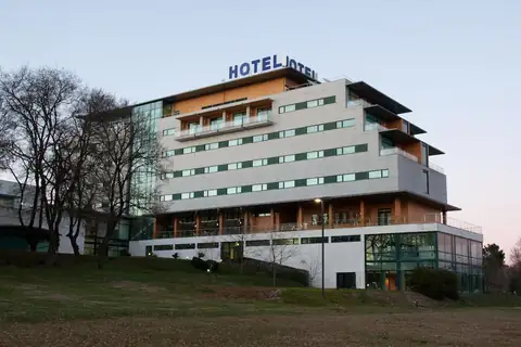 Fachada moderna del Exe Vía Argentum al atardecer rodeada de árboles en Silleda