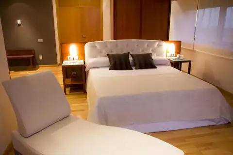 Habitación con cama de matrimonio y chaise longue blanca en el Exe Vía Argentum