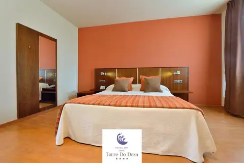 Habitación de matrimonio con pared naranja, cojines y armario en el Hotel Norat Torre do Deza