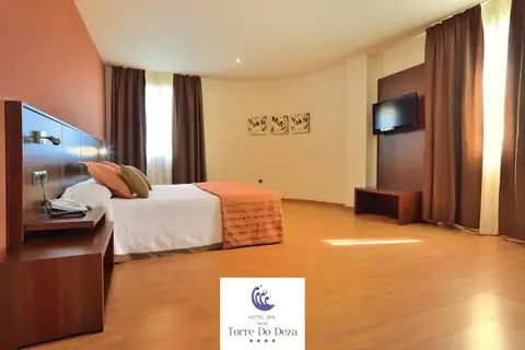 Habitación amplia con cama doble, televisión y suelo de madera en el Hotel Torre do Deza