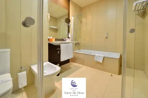 Baño con bañera, mampara de cristal y lavabo con toallas en el Hotel Spa Norat Torre do Deza