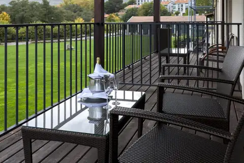 Terraza de habitación con sillones de mimbre y vistas al jardín en el Eurostars Vila de Allariz