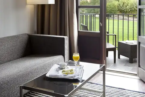 Zona de estar con sofá y desayuno junto a la terraza en una habitación del Eurostars Vila de Allariz