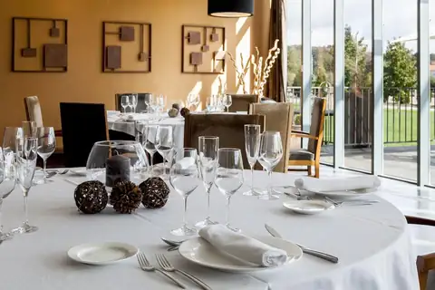 Restaurante con mesa redonda vestida y ventanales al jardín en el Eurostars Vila de Allariz