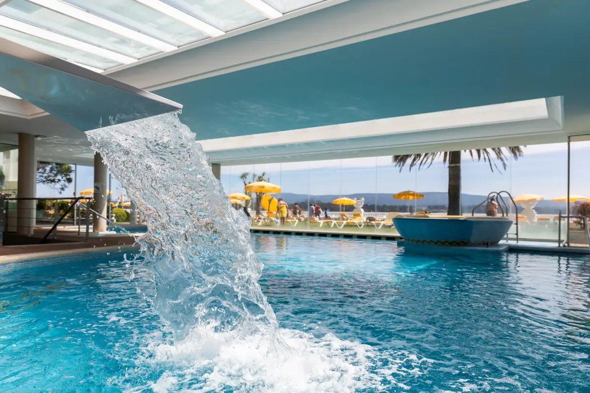 Piscina termal con cascada y vistas a la ría en un hotel balneario de La Toja