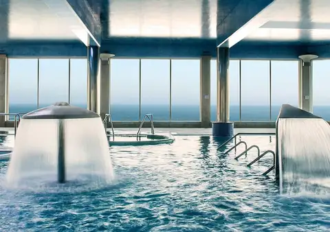 Piscina interior con cascadas y ventanales abiertos al océano en el Hotel Talaso Atlántico