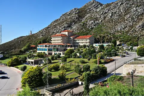 Vista del Hotel Talaso Atlántico y sus jardines al pie del monte en la costa de Oia