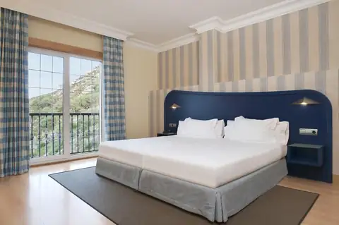 Habitación doble con cabecero azul y balcón con vistas en el Hotel Talaso Atlántico