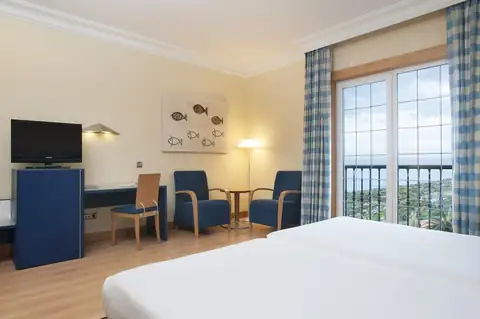 Habitación con zona de estar, televisión y ventanal luminoso en el Hotel Talaso Atlántico