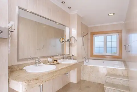 Baño con doble lavabo de mármol y bañera junto a la ventana en el Hotel Talaso Atlántico