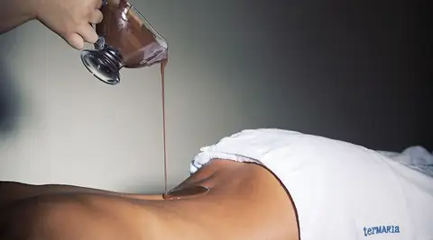 Aplicación de chocolate sobre la espalda en un tratamiento de Termaria Casa del Agua