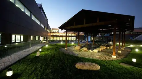 Jardín exterior con pérgola de madera y piedras iluminadas al anochecer en Termaria