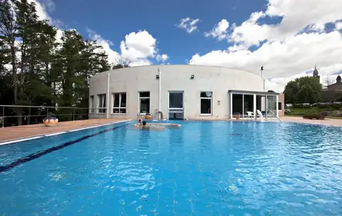 Piscina exterior al aire libre frente a un edificio circular blanco en Termas de Cuntis