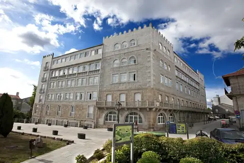Edificio histórico de granito con almenas y jardín de entrada del hotel de Termas de Cuntis