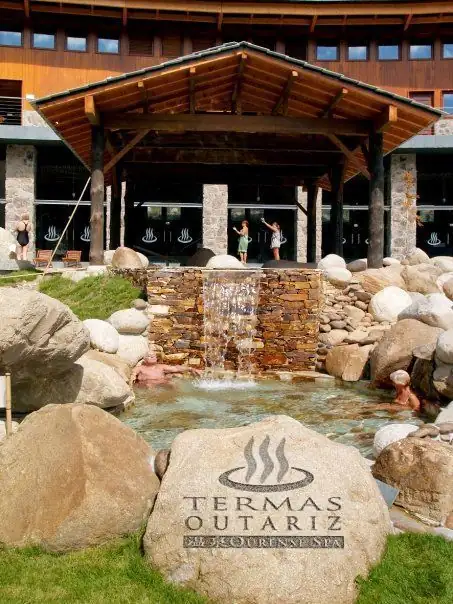 Fuente de piedra y roca grabada con el logotipo a la entrada de Termas Outariz