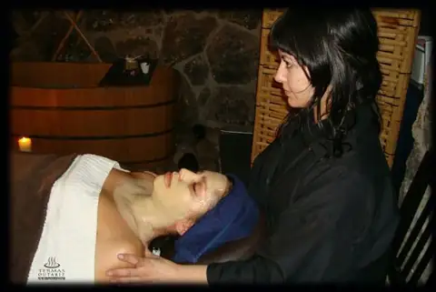 Masaje en cabeza y cuello en una sala de tratamiento con muros de piedra de Termas Outariz